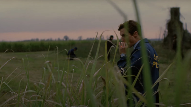 Matthew McConaughey's Rustin Cohle smokes a cigarette in a field in True Detective