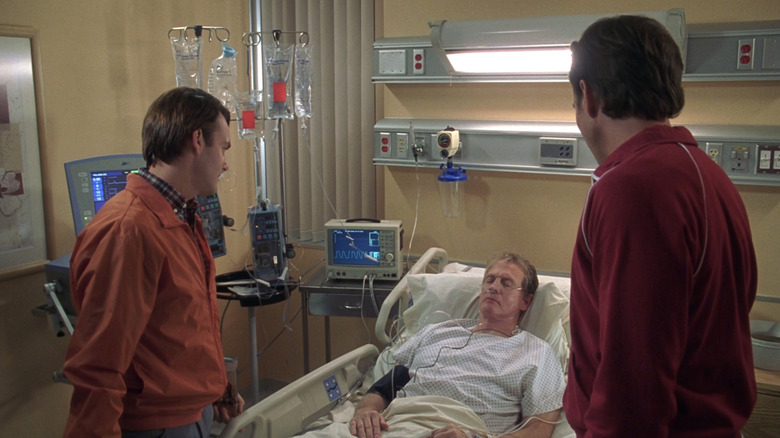 Will Forte's Dean Solomon and Will Arnett's John Solomon stand in a hospital room as Lee Majors' Ed Sullivan lays in bed in The Brothers Solomon