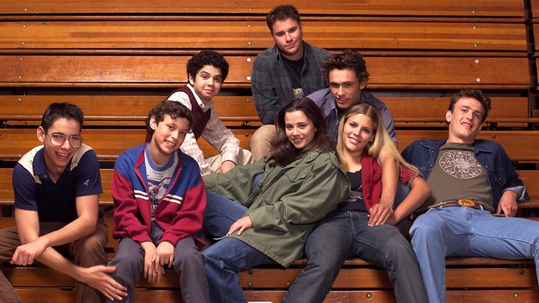 The cast of Freaks and Geeks sitting on bleachers 