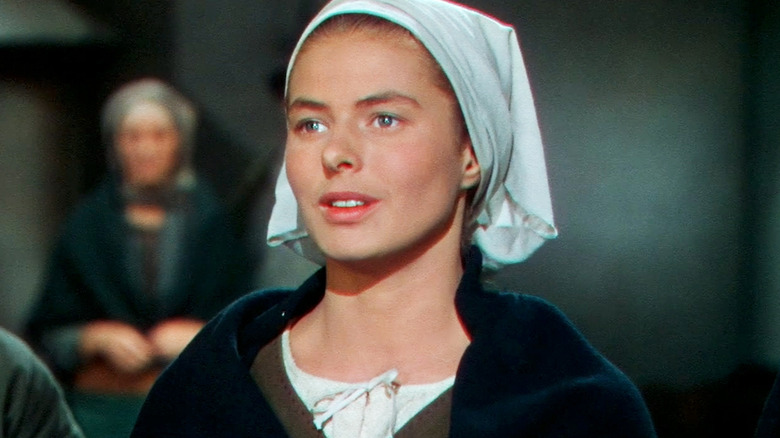 Ingrid Bergman's Joan of Arc is seen standing with her hands on her chest in Joan of Arc