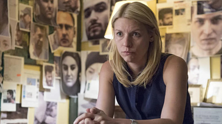 Claire Danes as Carrie Mathison, sitting in a room of photos on Homeland
