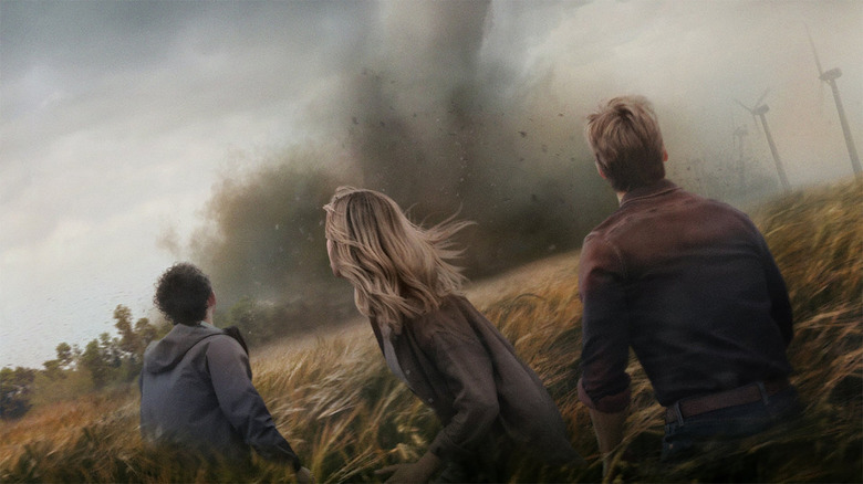 A trio stands staring at a tornado in a field in Twisters