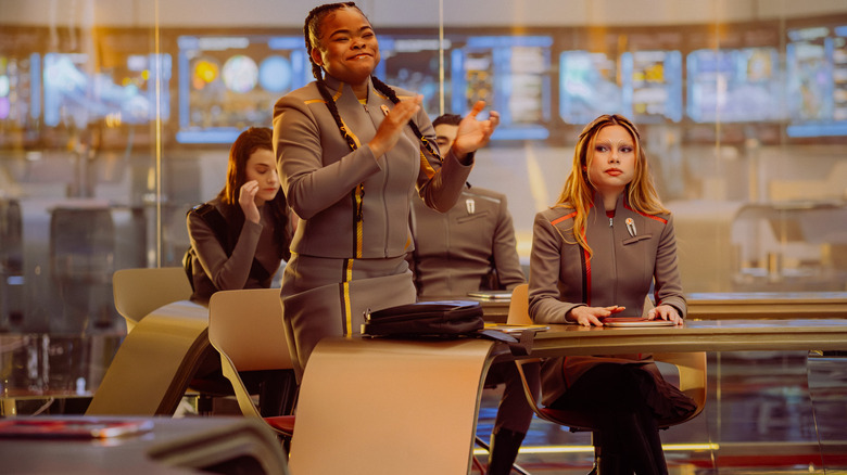 Kerrice Brooks as Sam standing and clapping at her desk next to Zoë Steiner as Tarima, Bella Shepard as Genesis, and Romeo Carere as Ocam in Star Trek: Starfleet Academy