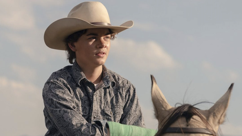 Brecken Merrill as Tate Dutton sitting on a horse in Yellowstone