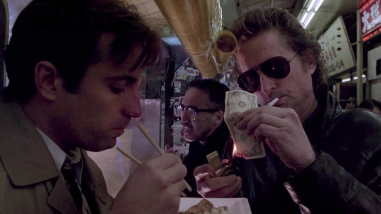 Nick Conklin (Michael Douglas) burns $100 and smokes a cigarette while Charlie (Andy Garcia) eats food in Black Rain