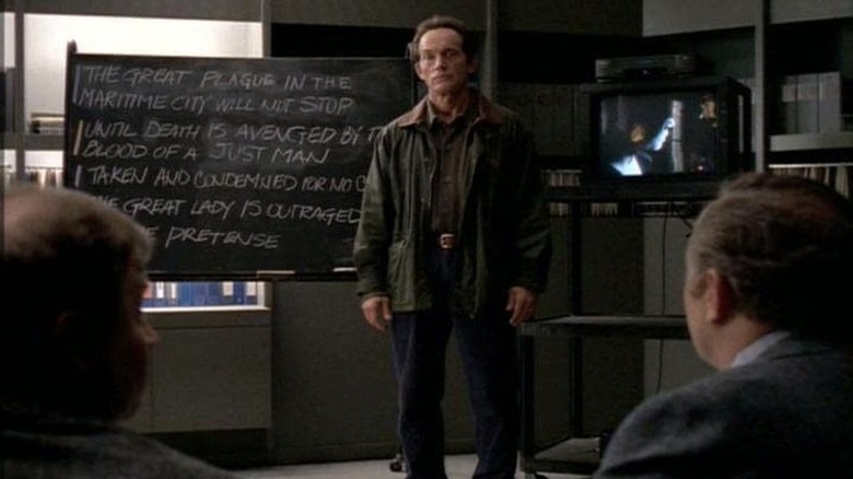 Lance Henriksen in front of chalkboard Millennium