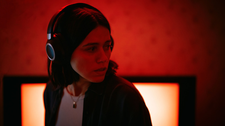Evy wears headphones and is bathed in red light in undertone