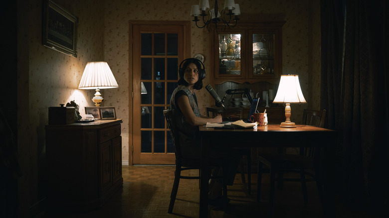 Evy looks around nervously while podcasting in undertone