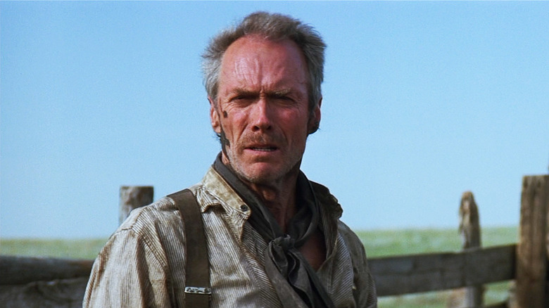 William Munny de Clint Eastwood regarde au loin alors qu'il se tient dehors dans Unforgiven
