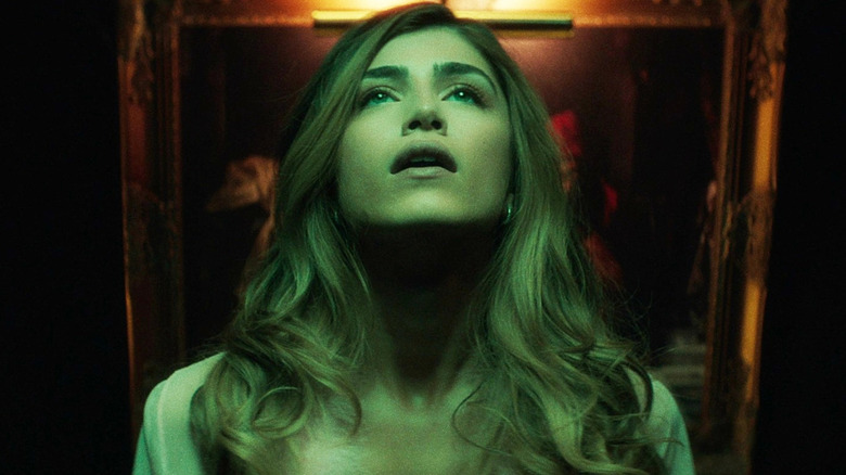 Maddie Hasson as Sage in Bone Lake, looking up at something and bathed in green light.