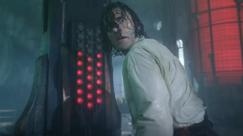 Oscar Isaac as Victor Frankenstein in Frankenstein, looking through his soaked hair in the pouring rain in front of some kind of strange scientific machinery.