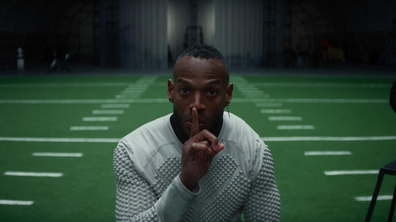 Marlon Wayans as Isaiah White in Him, centered in the frame and putting his finger over his mouth to "shh" someone.