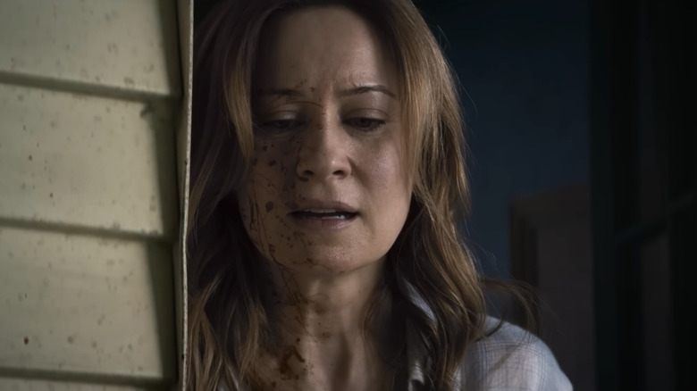 Camille Sullivan as Mia in Shelby Oaks, looking down with a bloodied face.