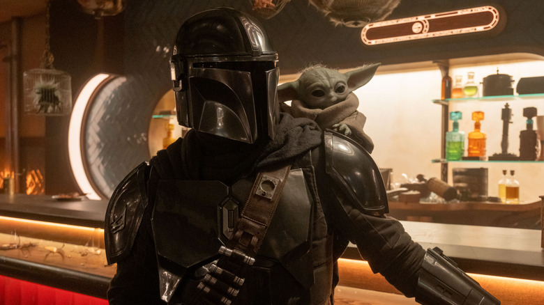 Mando with Grogu on his shoulder while he's standing at a bar in The Mandalorian and Grogu