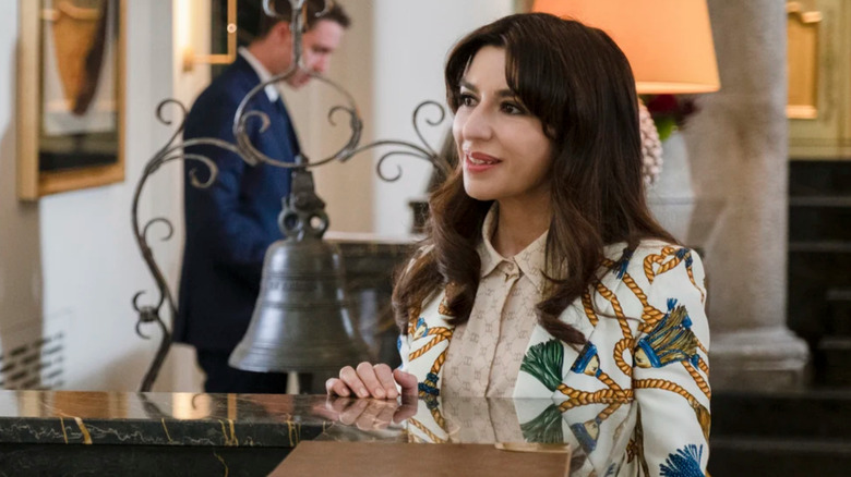 Valentina smiling at the hotel desk in The White Lotus