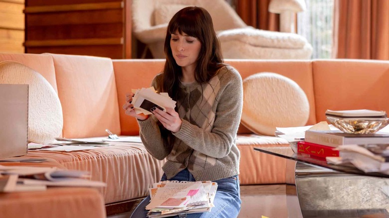 Lowen looking at pictures and photos and papers in Verity's office in Verity