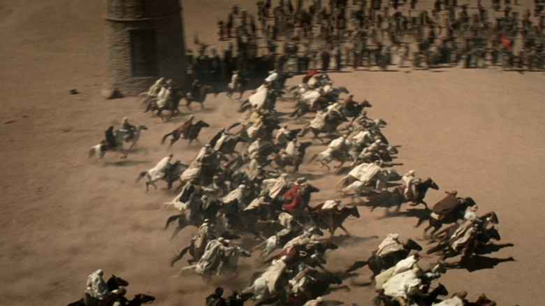 A top down view shows horse riders racing across a desert in Hidalgo