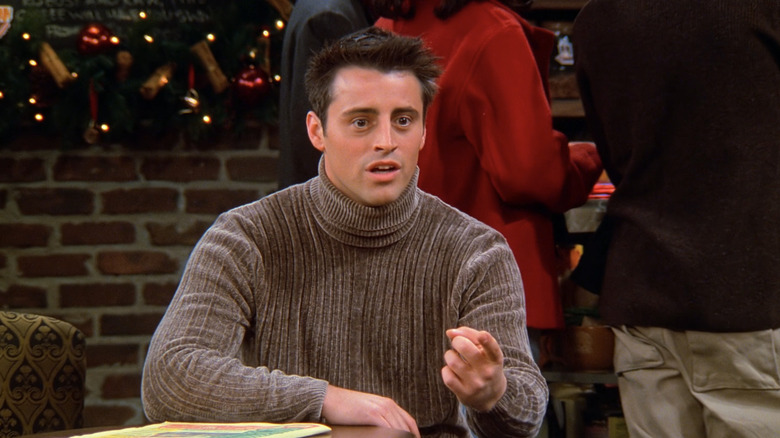 Matt LeBlanc as Joey Tribbiani points as he sits in a coffee house in Friends