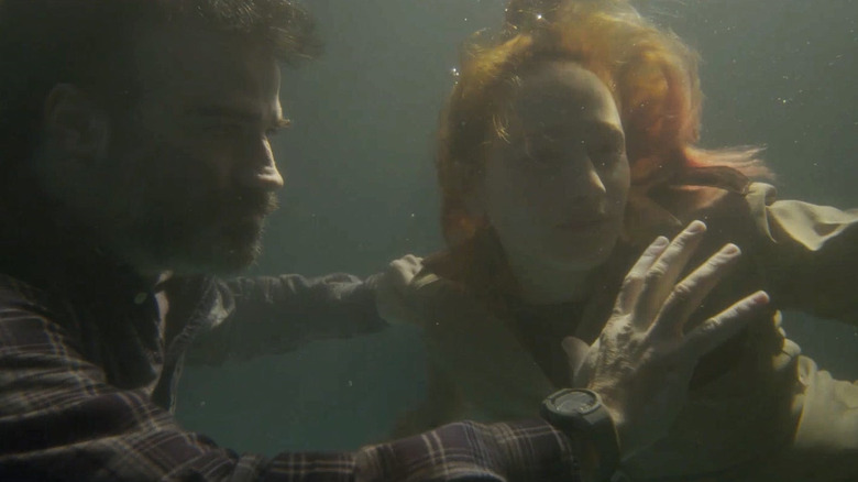 A survivor (Rasjid César) and Iris (Paula Silva) avoid zombies in Virus:32 (2022)