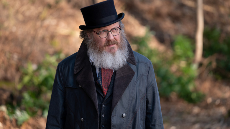 James Spader as Ultron in his human avatar wearing a top hat in a forested area in VisionQuest