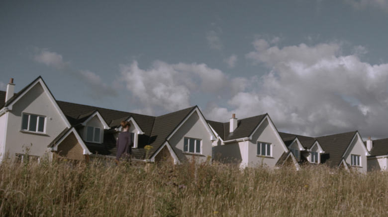 Ellen (Marie Ruane) walks past a row of identical houses in Foxes
