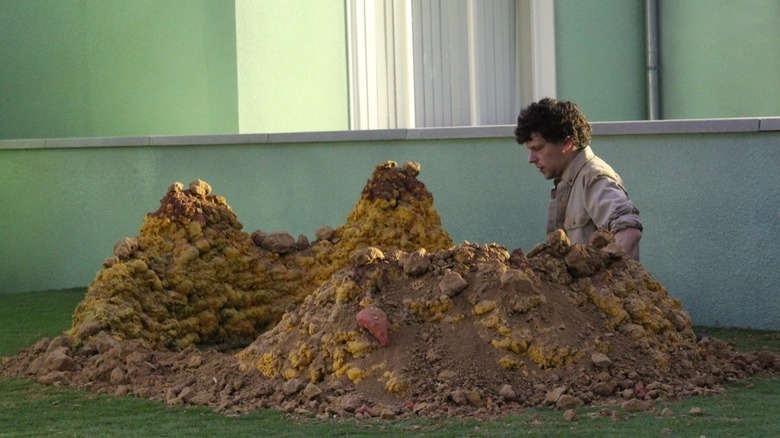 Tom (Jesse Eisenberg) standing in a whole he has dug in Vivarium