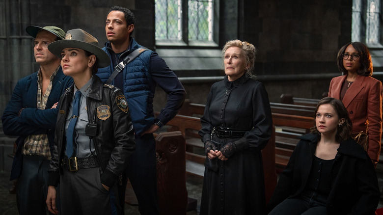 Andrew Scott as Lee Ross, Mila Kunis as Geraldine Scott, Daryl McCormack as Cy Draven, Glenn Close as Martha Delacroix, Kerry Washington as Vera Draven, and Cailee Spaeny as Simone Vivane crowded in front of church pews in Wake Up Dead Man: A Knives Out Mystery