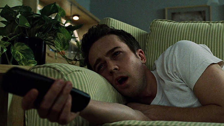 Edward Norton as the narrator sitting on the couch watching TV in Fight Club
