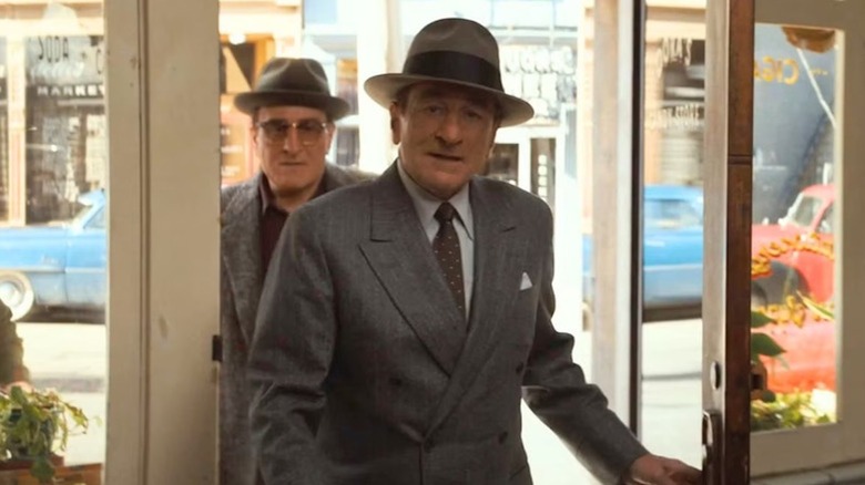 Robert De Niro as Vito Genovese and Robert De Niro as Frank Costello enter a shop in The Alto Knights