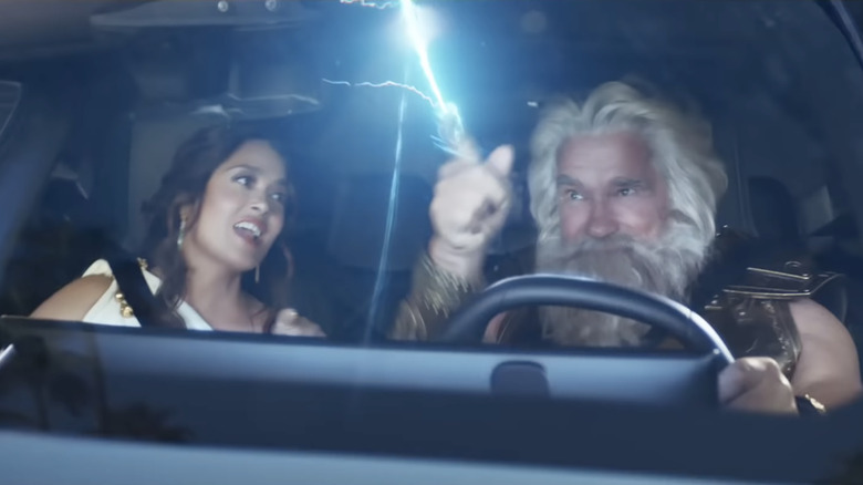 man with white hair and a beard with lightning coming out of his fingertip while driving next to a woman in a white dress