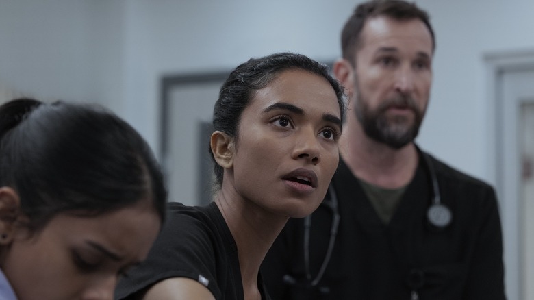 Mohan looking up surprised with Javadi in front of her and Robby behind her on The Pitt