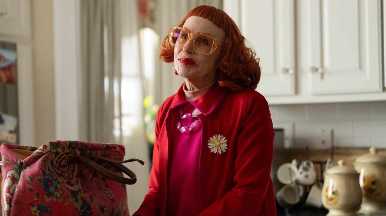 Gladys in Marcus' kitchen smiling next to her handbag in Weapons