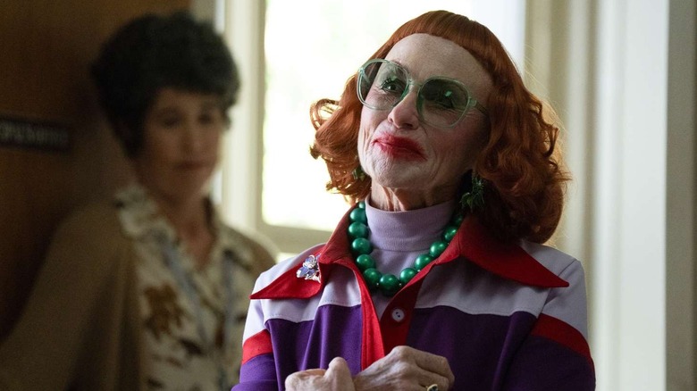 Gladys smiling with green glasses in Marcus' office on Weapons