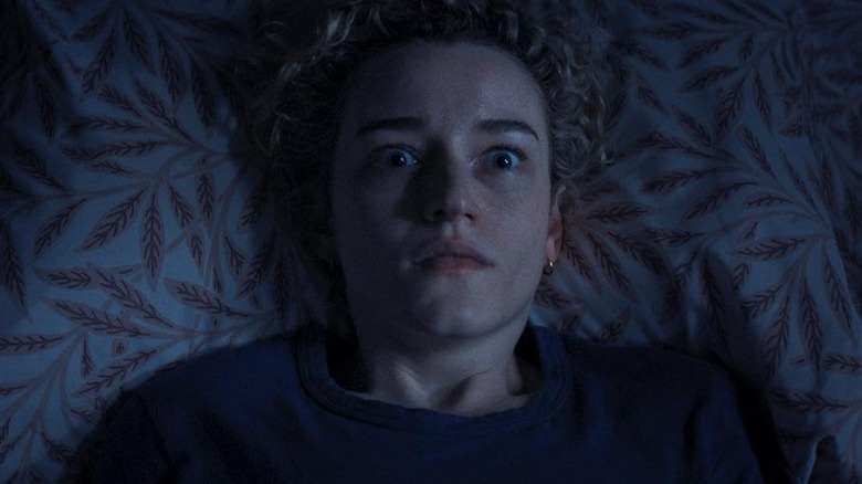 Julia Garner é apenas dormir na cama olhando para o rosto com armas