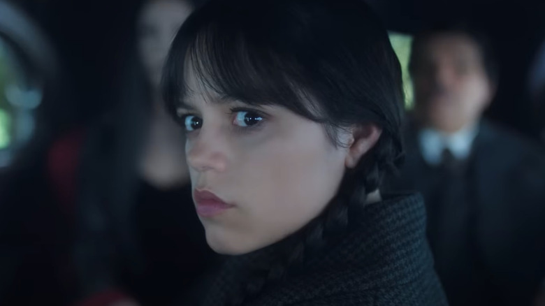 Jenna Ortega as Wednesday sitting in a car with her parents in Wednesday