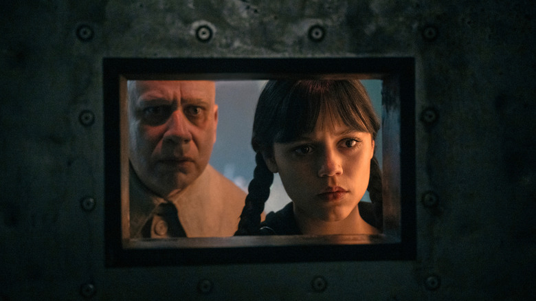 Uncle Fester and Wednesday peer into a cell window in Wednesday
