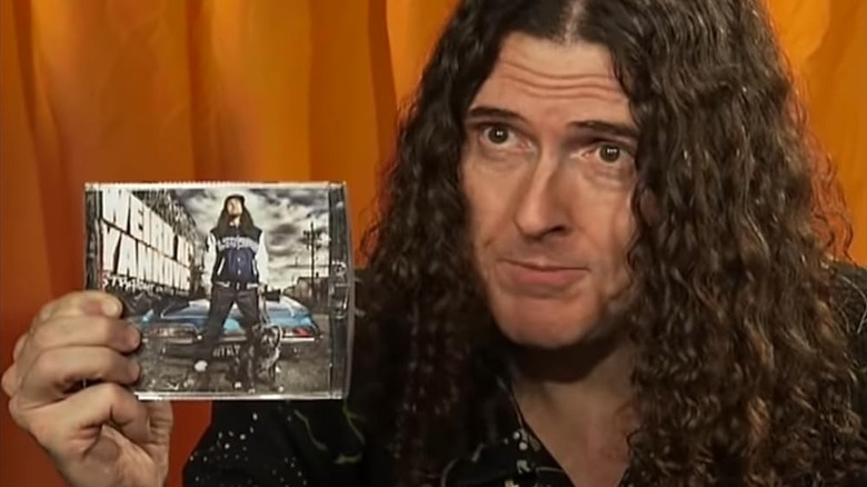 "Weird Al" Yankovic holding up his album Straight Outta Lynwood on an episode of Al TV