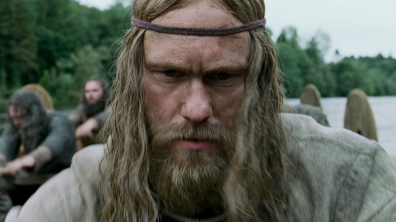 Alexander Skarsgård as Amleth looking serious as he rows a boat in The Northman