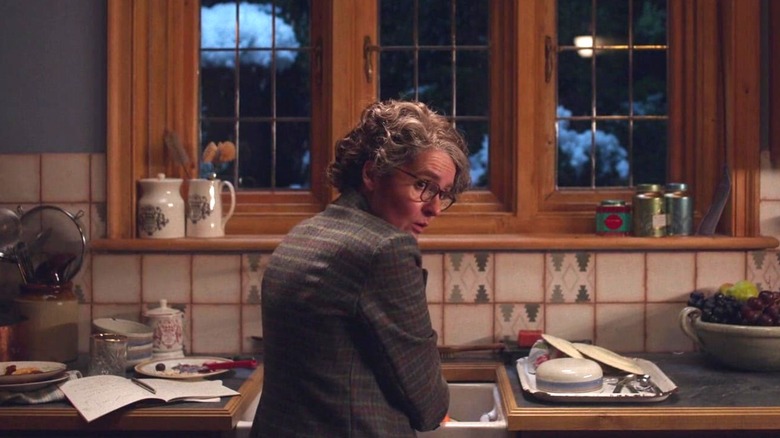 Agatha Christie, as played by Shirley Henderson, looking over her shoulder in a kitchen in See How They Run