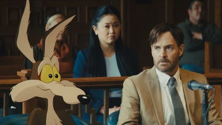Wile E. Coyote sitting next to Will Forte as Kevin Avery in court in Coyote vs. Acme