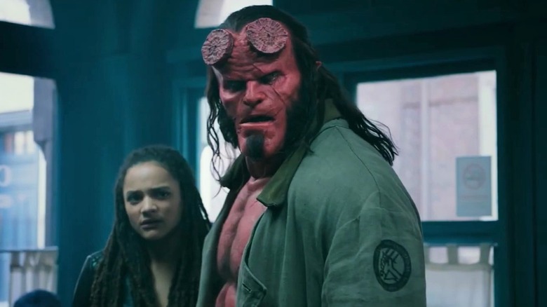 Hellboy holding his jaw open and standing with Alice Monaghan in Hellboy (2019)