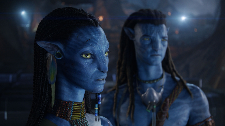 ஜோ சல்தானா நெய்திரியாக சாம் வொர்திங்டனுடன் ஜேக் சல்லியாக அவருக்குப் பின்னால் அவரது இடதுபுறத்தில் நிற்கும் அவதாரம்: நெருப்பு மற்றும் சாம்பல்