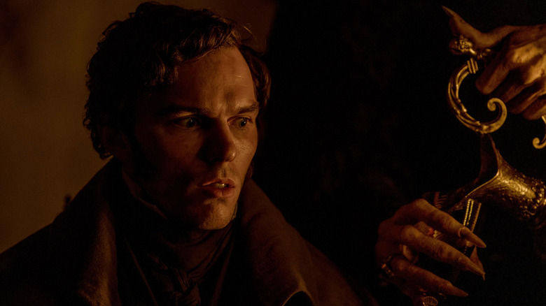 Nicholas Hoult as Thomas Hutter looks horrified as Count Orlock pours him a Nosferatu potion