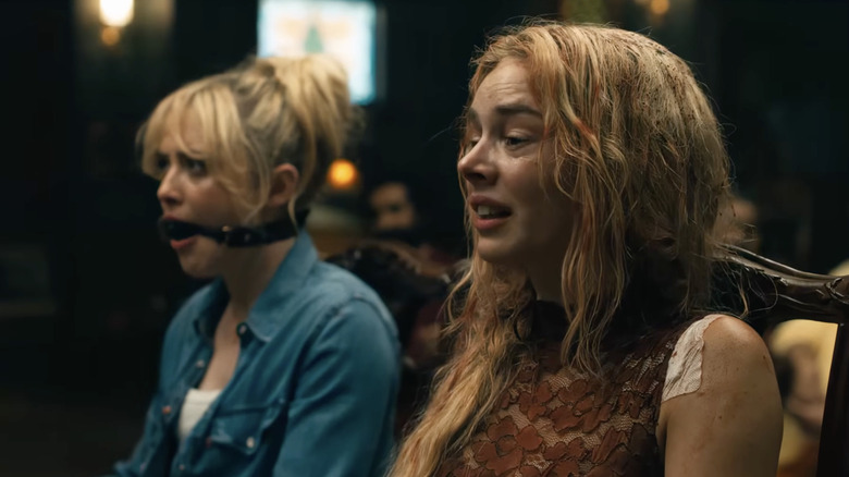 ఫెయిత్‌గా క్యాథరిన్ న్యూటన్ మరియు రెడీ లేదా నాట్ 2లో గ్రేస్ కలిసి కుర్చీల్లో బంధించబడి సమారా వీవింగ్: హియర్ ఐ కమ్