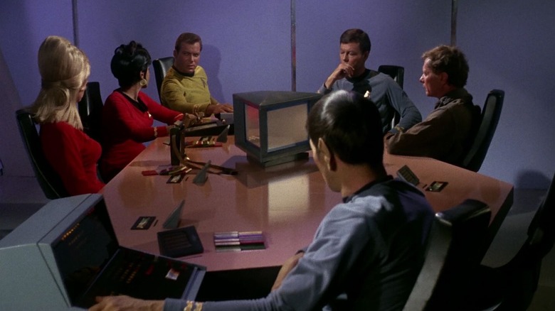 Six people around a conference table on Star Trek