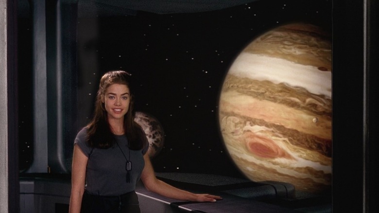 Denise Richards as Carmen Ibanez in Starship Troopers, in front of a window giving a view of Jupiter