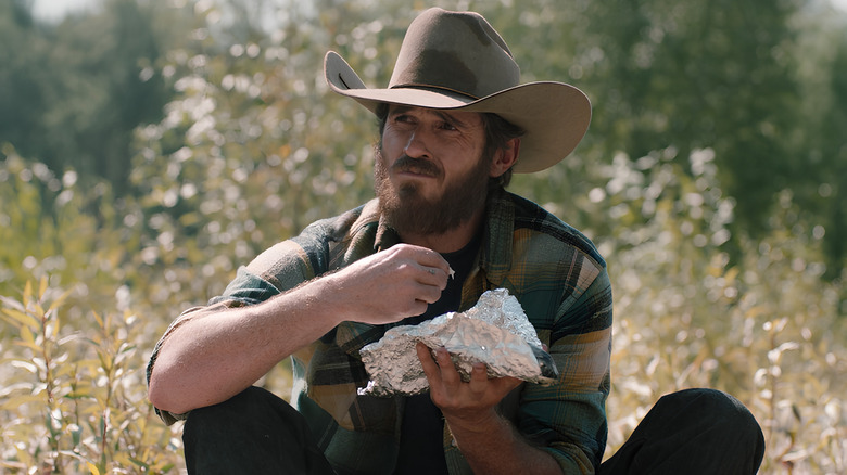 Lee Dutton sitting down and holding tinfoil in "Yellowstone"