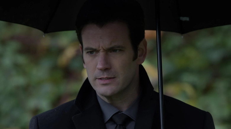 Colin Donnell as Tommy Merlyn, carrying an umbrella at a funeral on Arrow