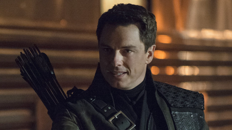 John Barrowman as Malcolm Merlyn, extending a hand on Arrow