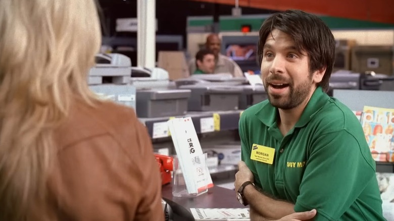 Joshua Gomez as Morgan on Chuck, in his Buy More uniform, leaning against a counter